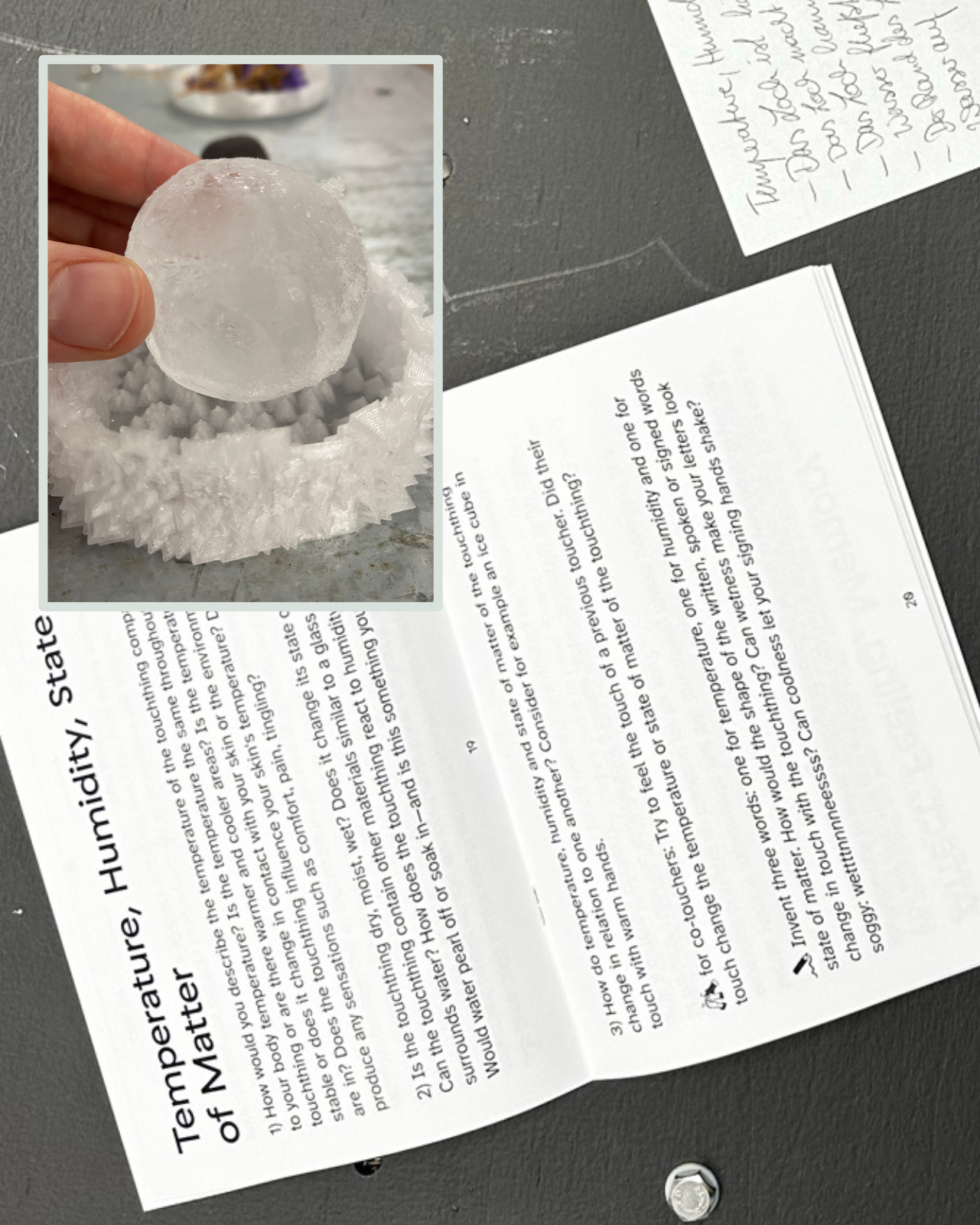 This photo collage shows the tactile descriptions workbook opened on a dark table display. The double page guides participants through writing exercises on temperature, humidity and state of matter. Some notes are placed next to the booklet. Atop, another photo is visible. This photo is smaller on shows a hand touching a round, frosty ice cube that lies within a 3D printed spiky holder.